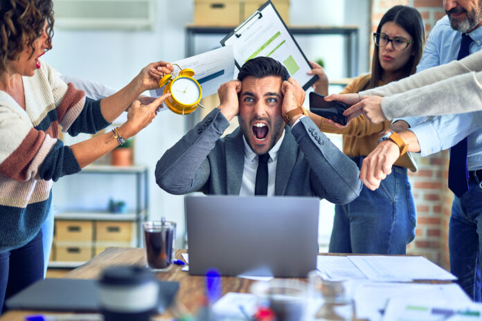 Man stressed at work being pressured by co-workers.