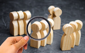 Groups of wooden people and a magnifying glass. The concept of market segmentation.